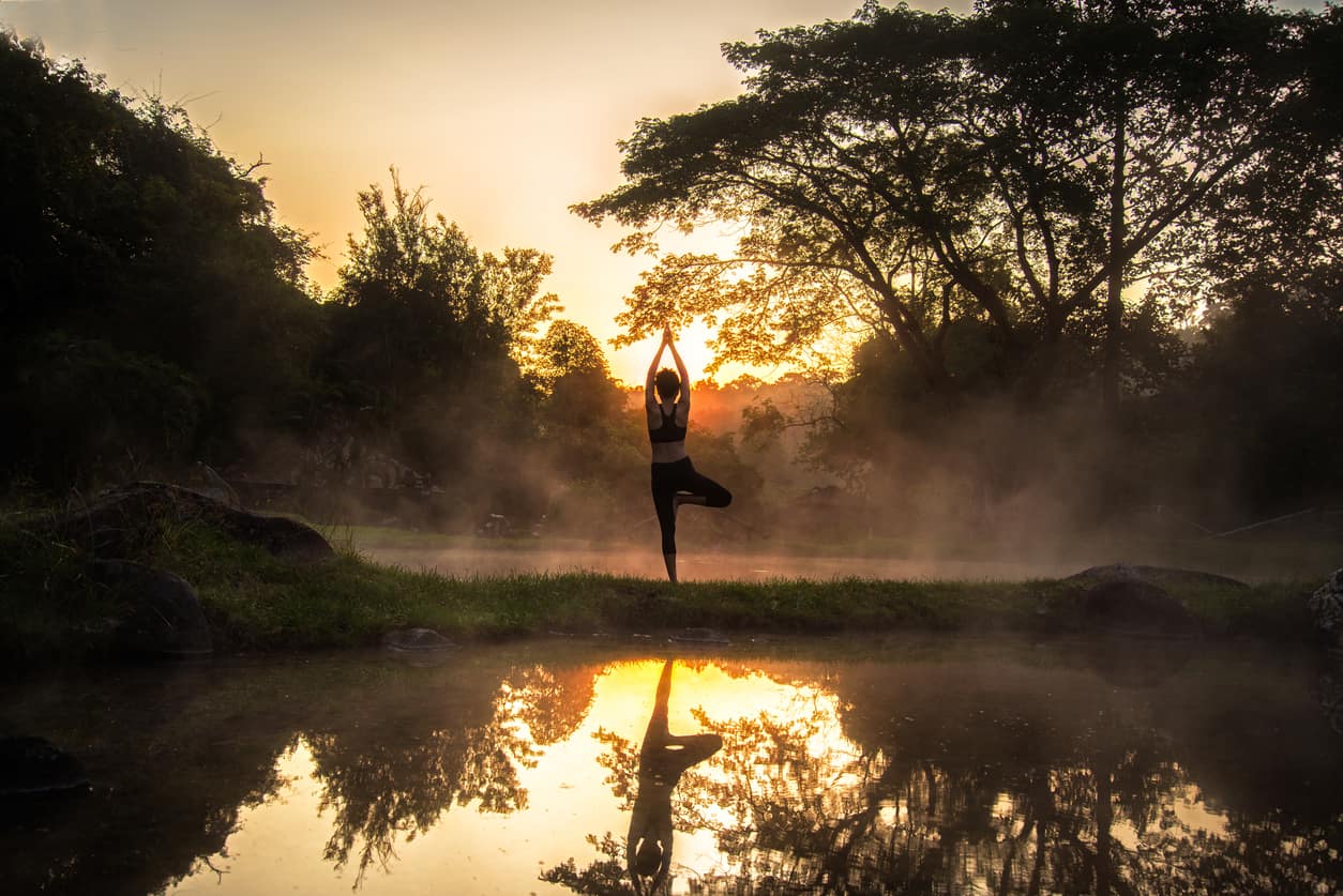 Silhouette of a beautiful Yoga healty woman in the morning at the hot spring park.  Healty Concept