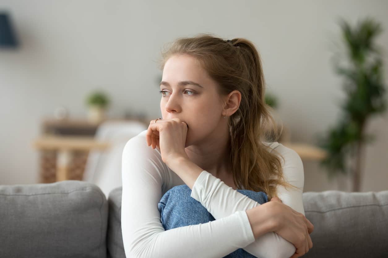 Sad woman sitting on couch alone at home