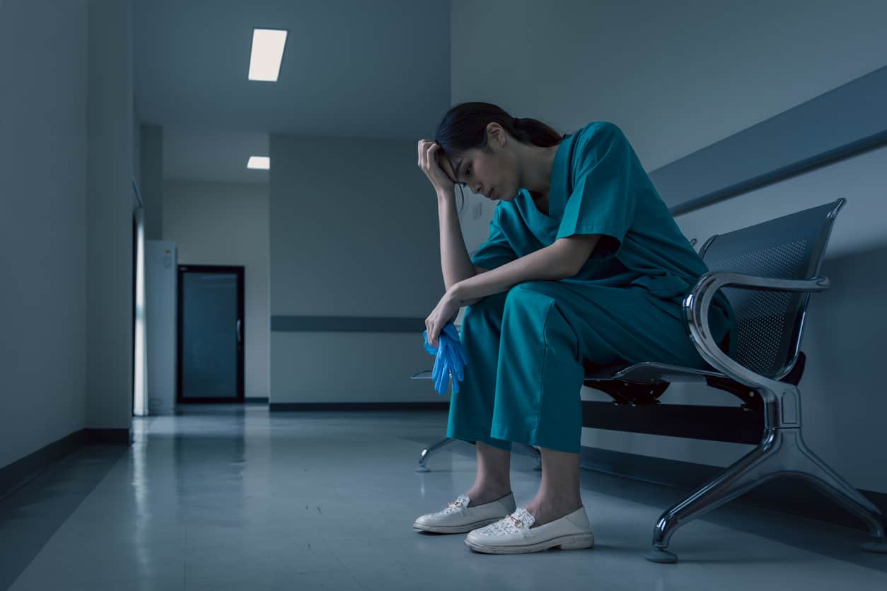 Medical nurse is sitting down a the hospital corridor in frustration and grief after failure and patient body condition concept