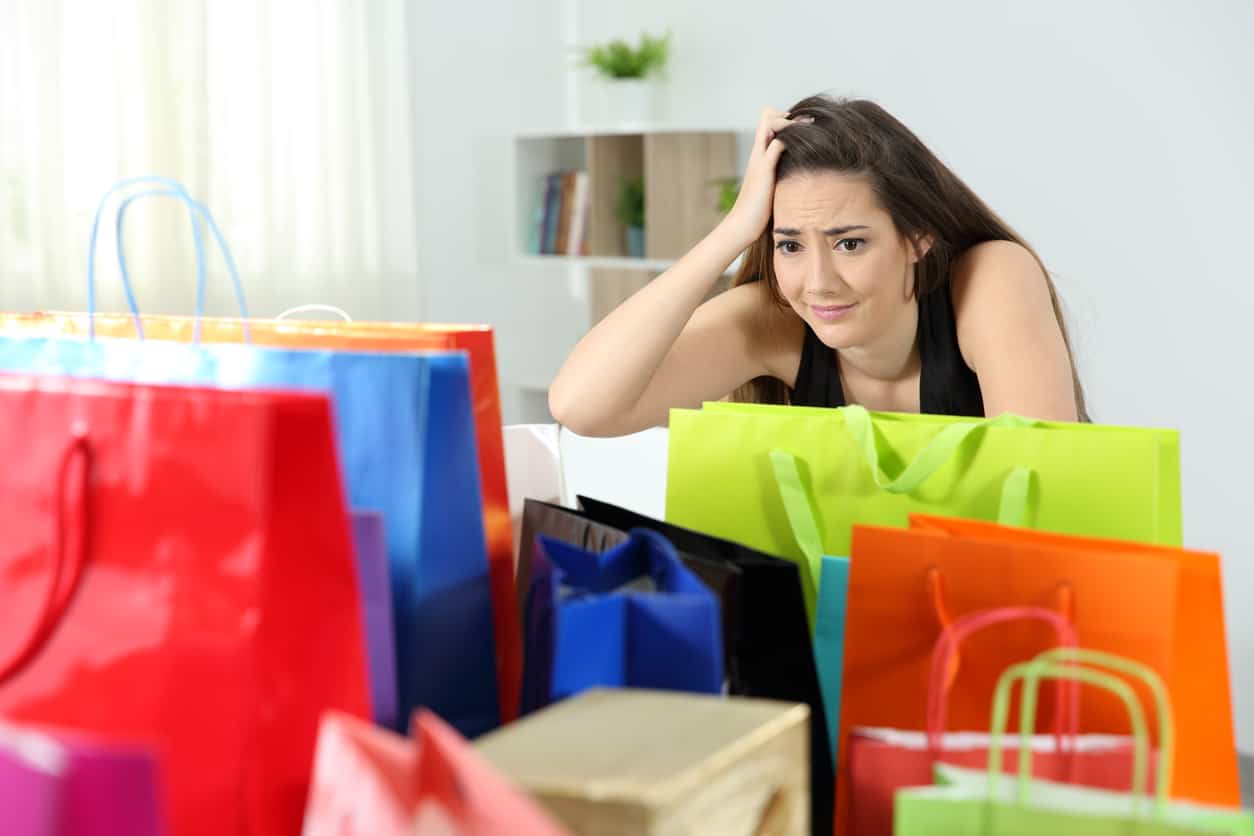 Worried shopaholic woman after multiple purchases